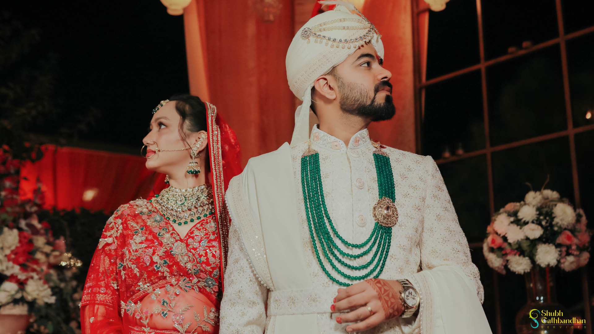 Anand in his ivory sherwani and turban beside Soumya in her red lehenga on the stage