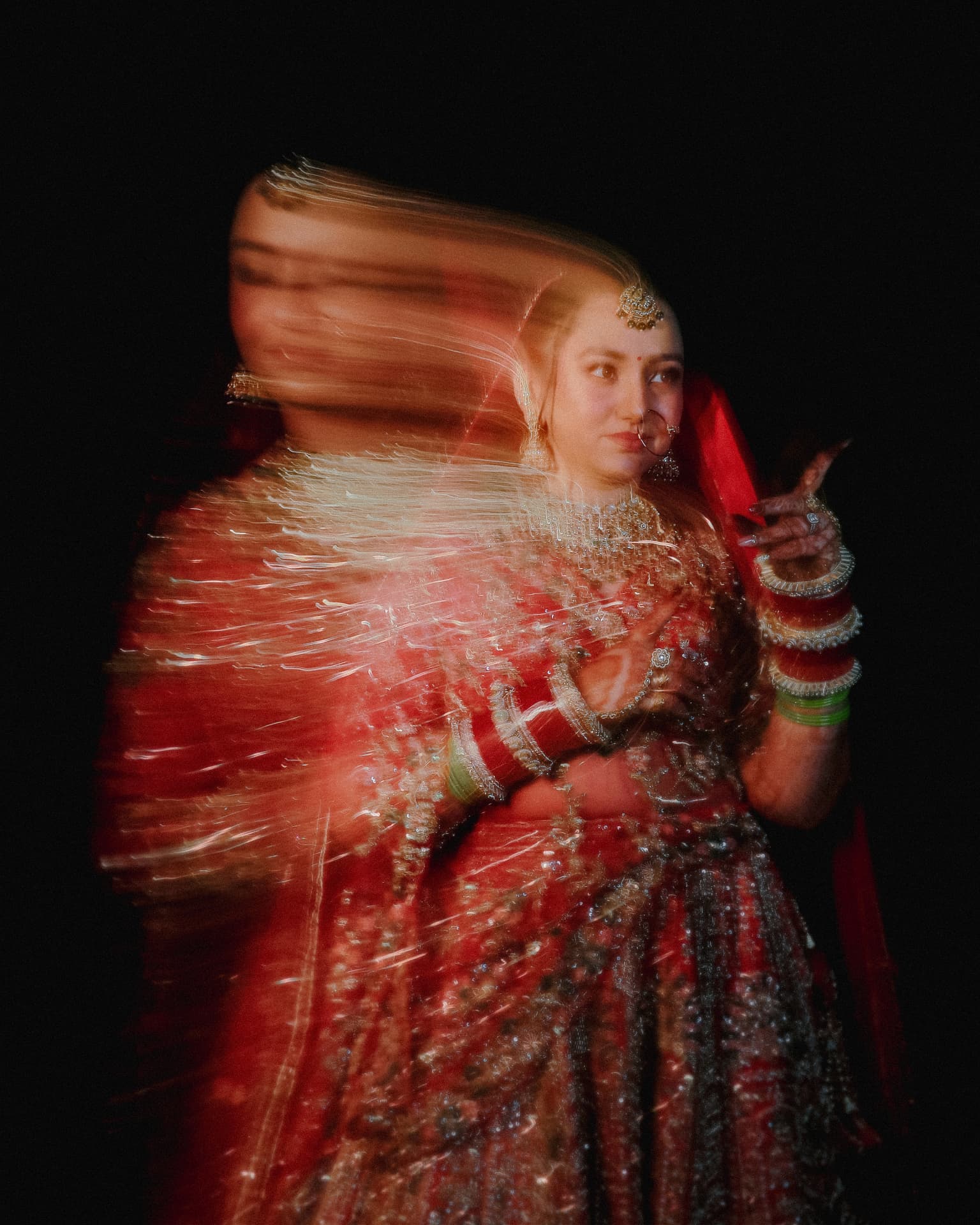 Soumya twirling in her red lehenga in a long-exposure portrait