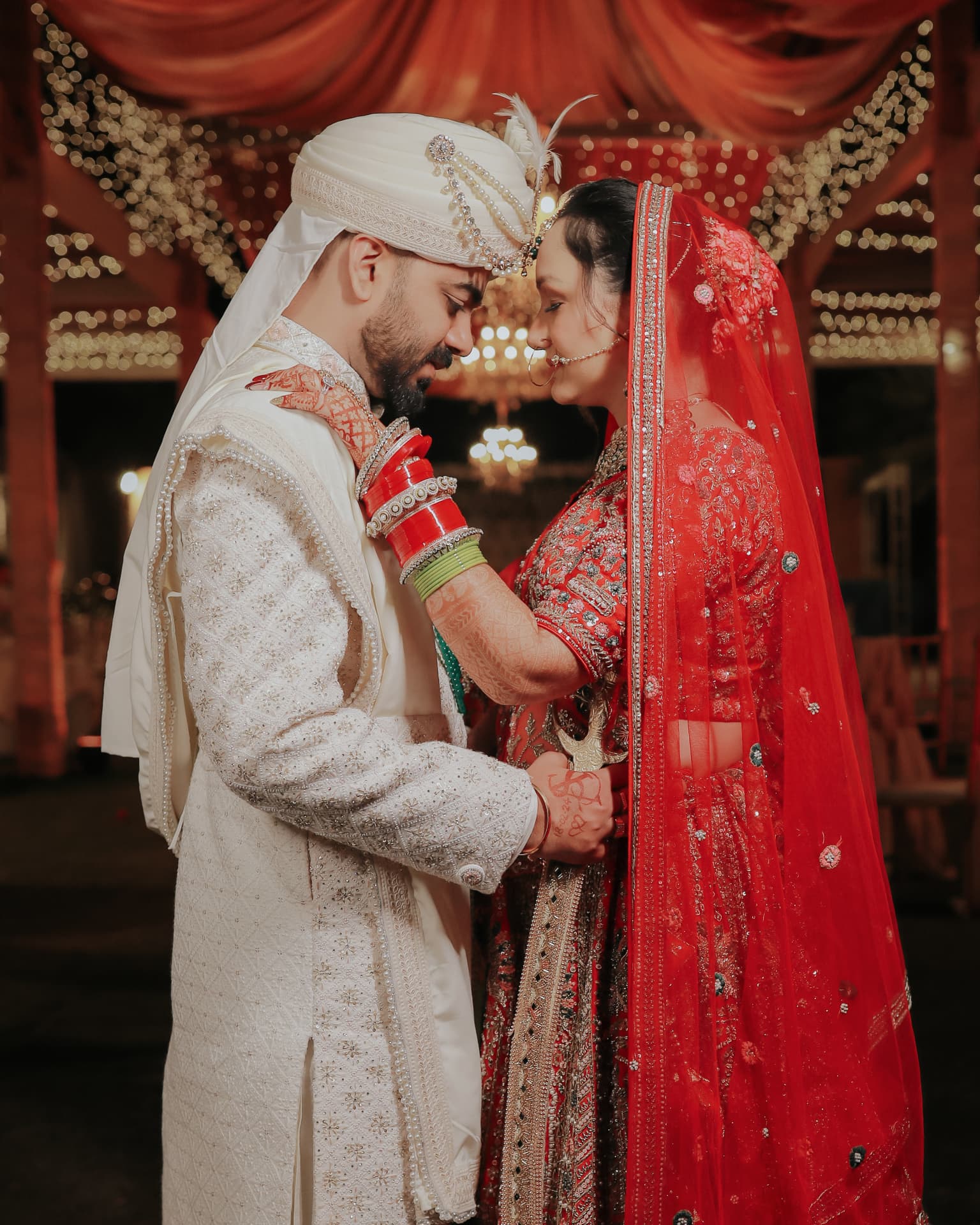 Anand and Soumya forehead to forehead beneath the lit mandap