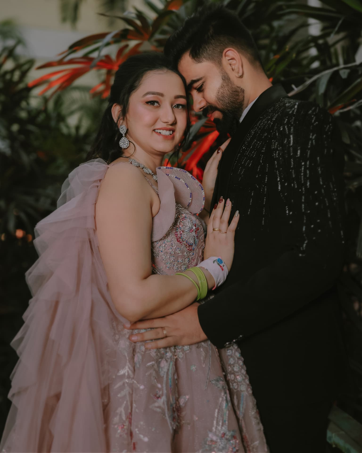 Anand and Soumya embracing among red foliage at their engagement