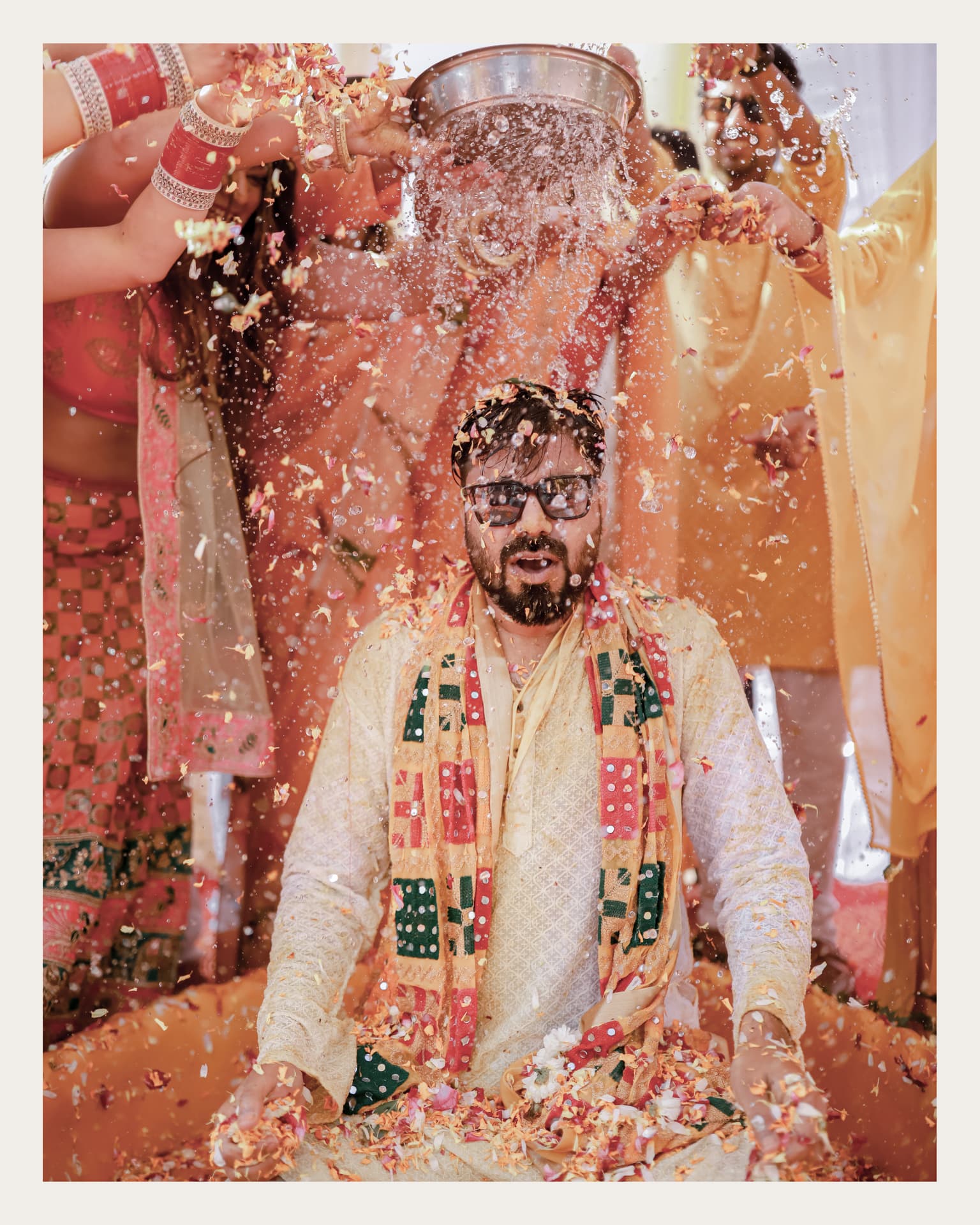 Water and flower petals poured over Anand during the haldi